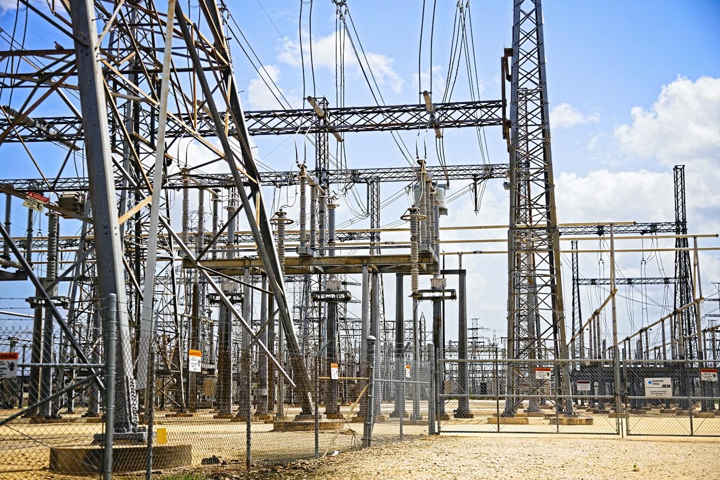 Steel lattice structures and high-voltage equipment inside a fenced substation
